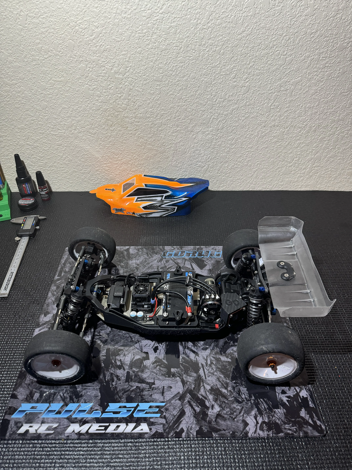 1/10 RC chassis on an acrylic pit board with a simulated forged carbon design