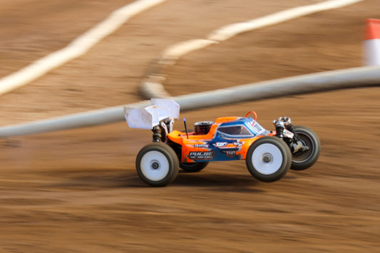 Orange RC buggy racing on a dirt track