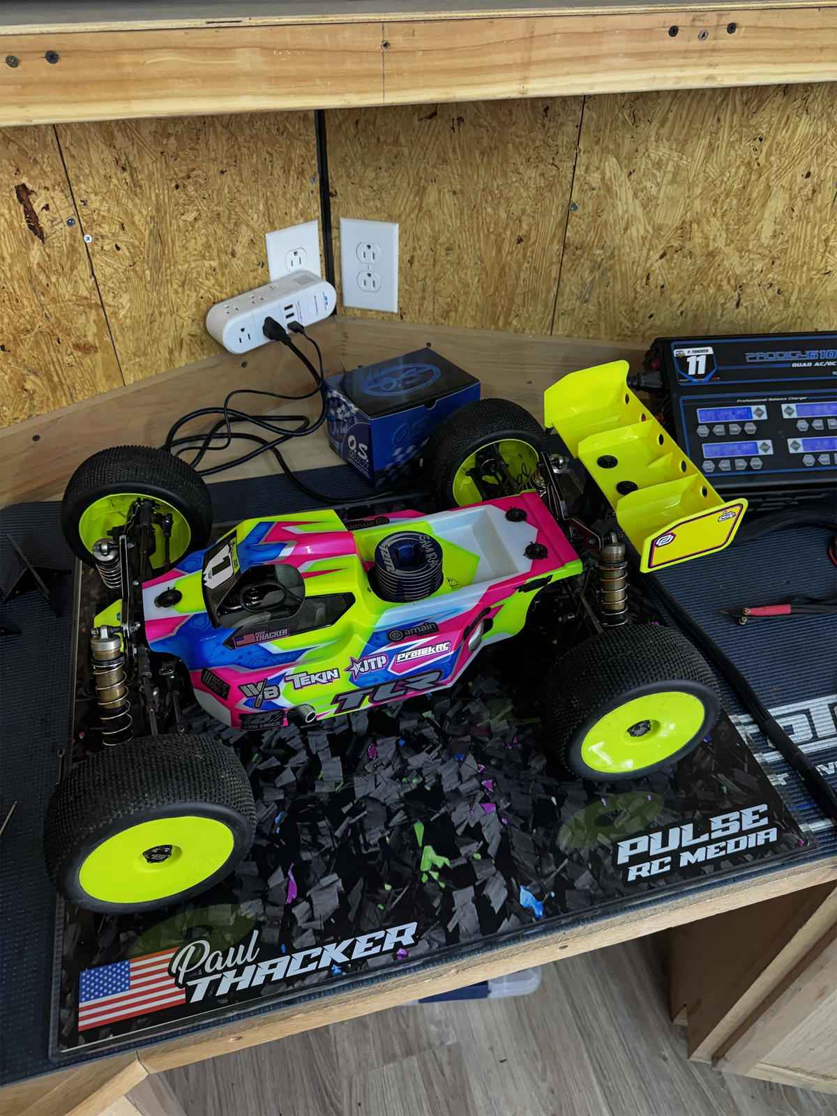 Custom RC pit board with a personalized name beneath a truggy on a workbench